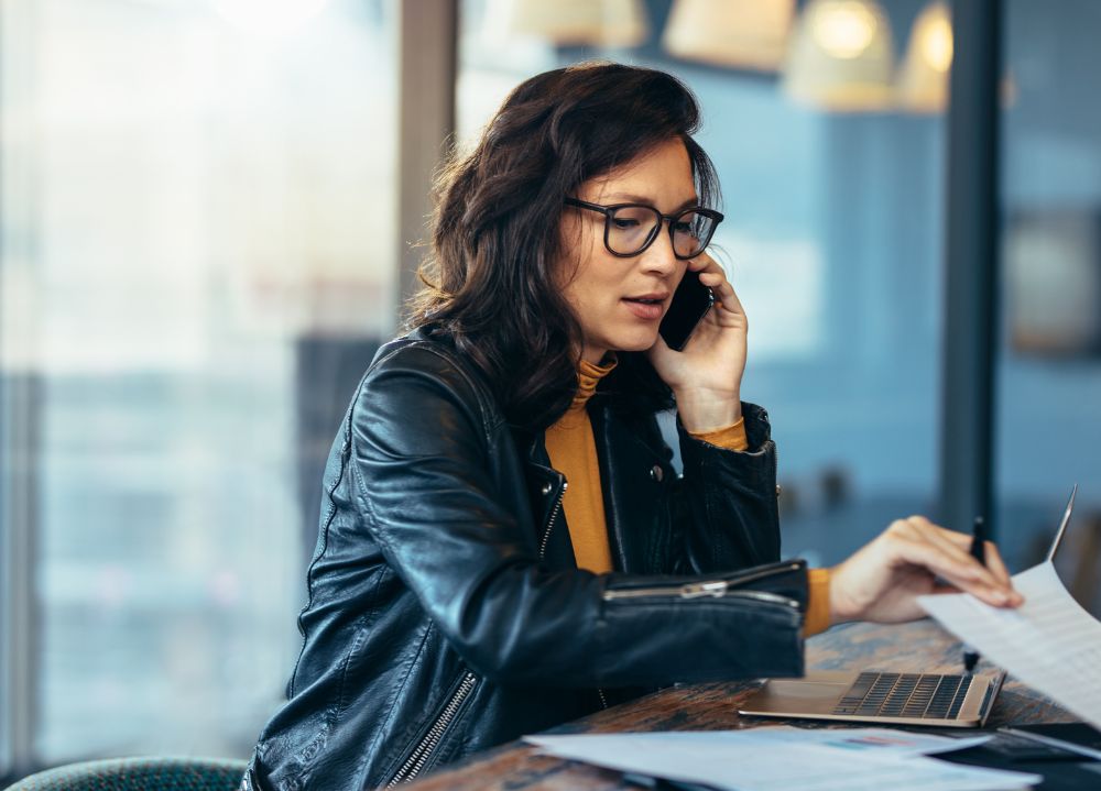 Business executive at her desk on the phone and typing on her laptop.